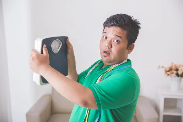 Shocked obese man while looking at a weight scale — Stock Photo, Image