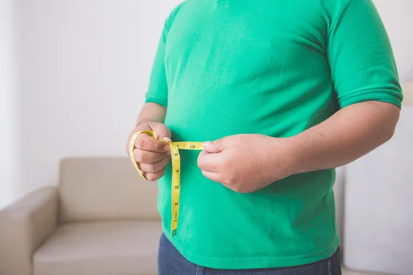 Homem com sobrepeso medindo sua barriga em casa — Fotografia de Stock