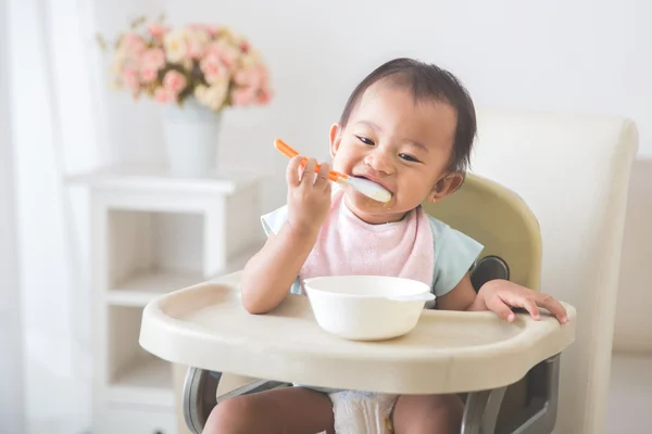 Bambina seduta sul seggiolone e nutrire se stessa — Foto Stock