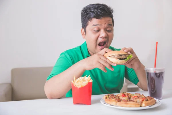Zwaarlijvige man eet junkfood — Stockfoto