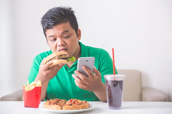 Жирний чоловік їсть нездорову їжу — стокове фото