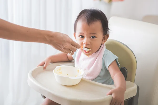 Felice giovane bambino in seggiolone essere alimentato — Foto Stock
