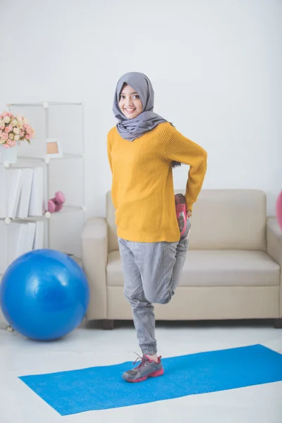 Kvinnan sträcker sig medan gör övning hemma — Stockfoto