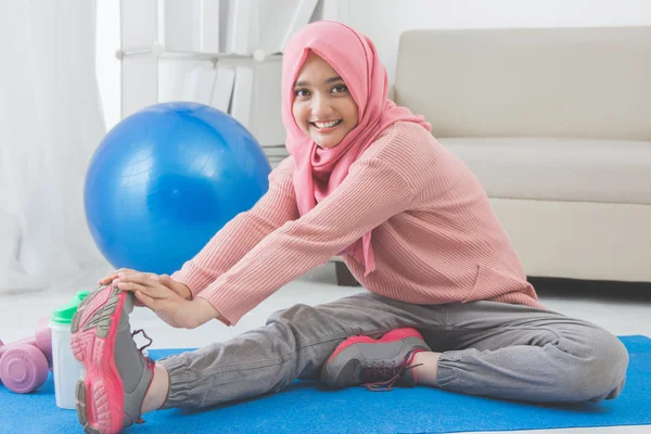 Mujer estiramiento mientras haciendo ejercicio en casa —  Fotos de Stock