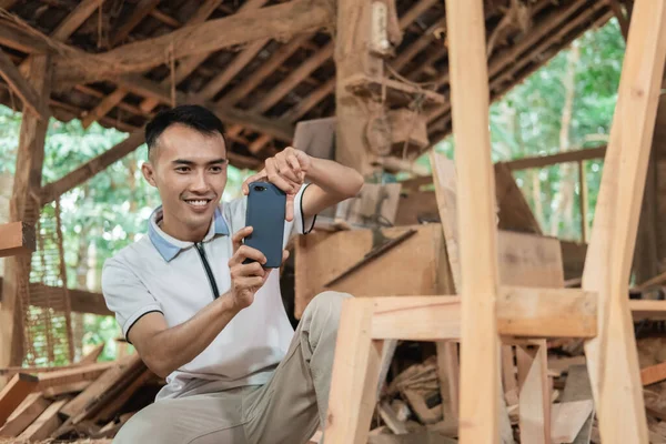 Asiate lächelt beim Fotografieren von Holzstühlen — Stockfoto