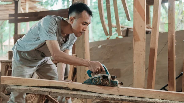 Ασιατικοί ξυλουργοί εργάζονται με ηλεκτρικά σπλάχνα ξύλου όταν λειαίνουν ξύλινες επιφάνειες — Φωτογραφία Αρχείου