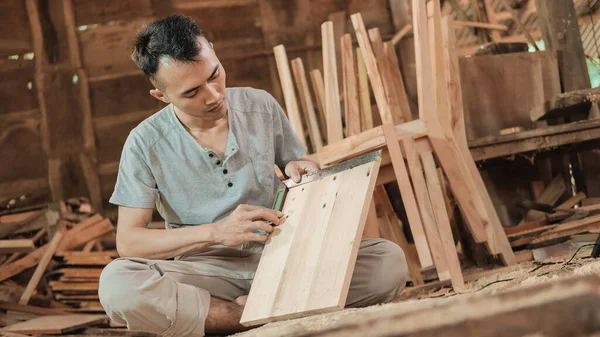 Carpintero sentado en el suelo sosteniendo una regla de codo carpintero —  Fotos de Stock
