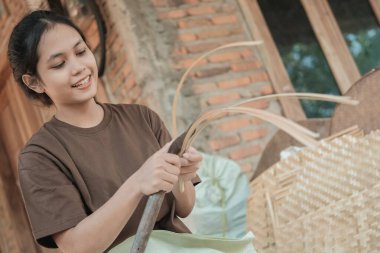 Asyalı kadınlar bambu çatalları yapmak için bıçak kullanırken gülümserler.