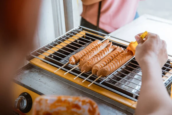 Junger Mann grillt eine Wurst — Stockfoto