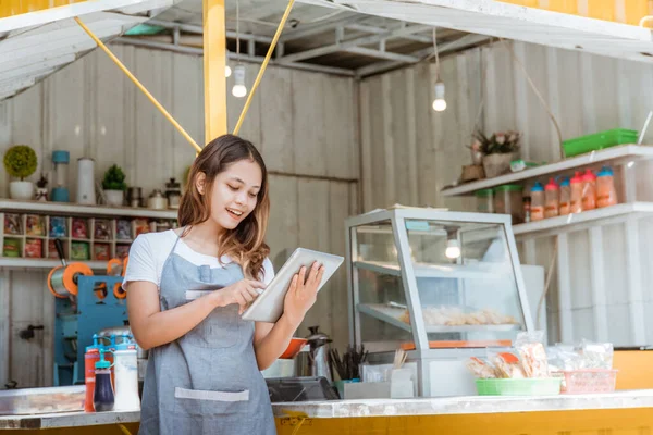 Vrouw nemen van online bestelling op haar kleine kraam winkel — Stockfoto