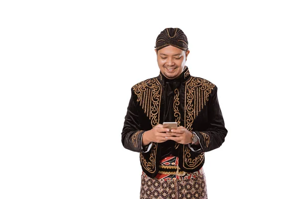 Retrato de un hombre javanés tradicional feliz sosteniendo un teléfono celular. — Foto de Stock