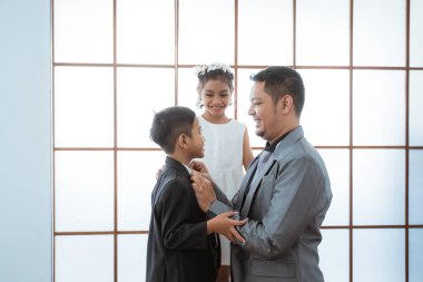 Bir babanın portresi. Oğullarının elbiselerini düzenliyor..