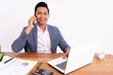 Çekici ve neşeli genç bir iş adamı cep telefonu tutuyor ve otururken gülümsüyor..