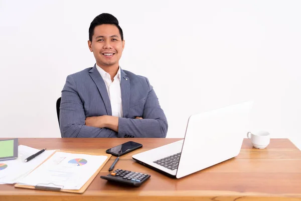 En attraktiv och glad ung affärsman som arbetar på en bärbar dator och ler sittande. — Stockfoto