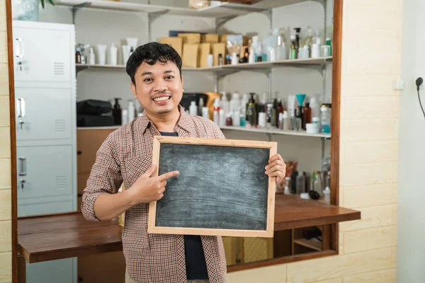 Portrét mladý muž prodávající balené výrobky držící tabuli — Stock fotografie