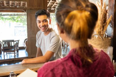Genç adam garsonlarla konuşuyor.