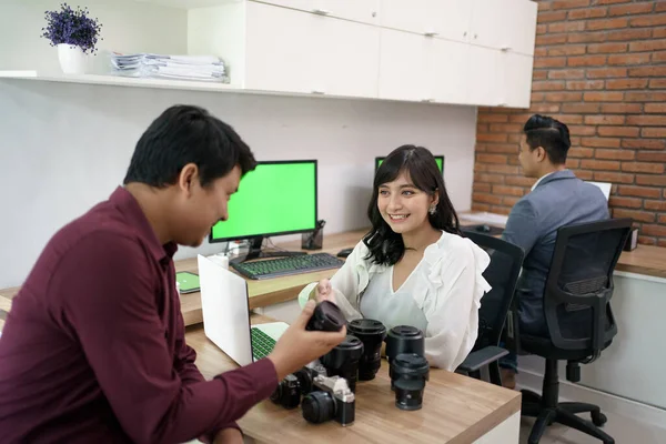 Service à la clientèle expliquant le produit sur la caméra magasin de location d'équipement — Photo