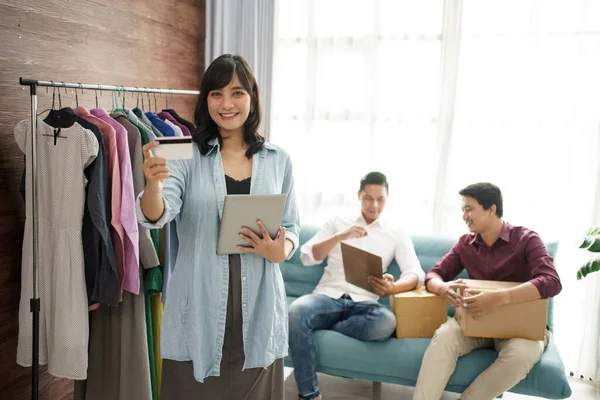 Un retrato de una joven empresaria en una tienda de ropa con un equipo. — Foto de Stock