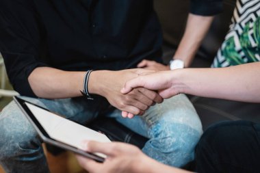 İki adamın tokalaşma tabletini tutarken el sıkışın.