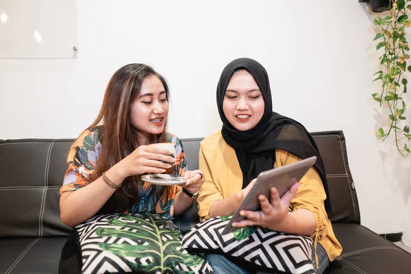 Two girl friends using tablet and drink a coffee — Stock Photo, Image