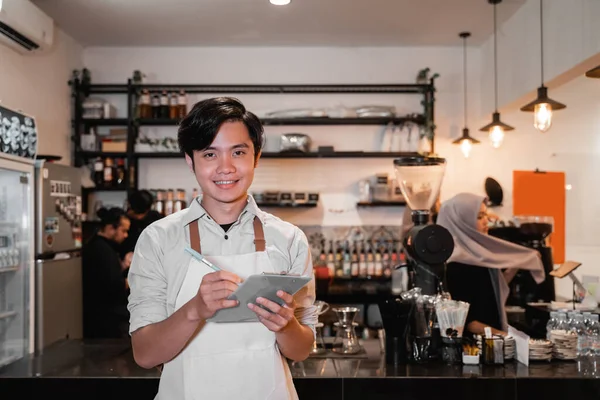 Serveerster glimlachen en vasthouden nota voor schrijven klanten orders — Stockfoto