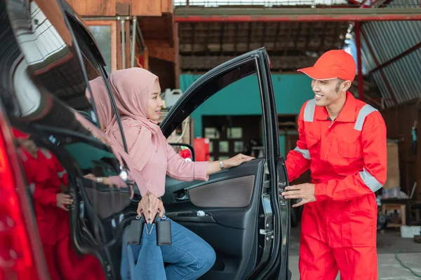 Ο μηχανικός με την κόκκινη στολή κλείνει την πόρτα του πελάτη αφού επισκευαστεί το αυτοκίνητο. — Φωτογραφία Αρχείου