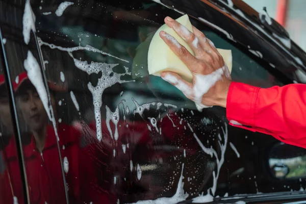 close up of car cleaner hands cleaning the windshield with a sponge
