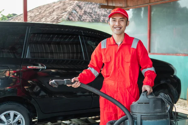 Man bil renare bär röd uniform stående bär dammsugare — Stockfoto