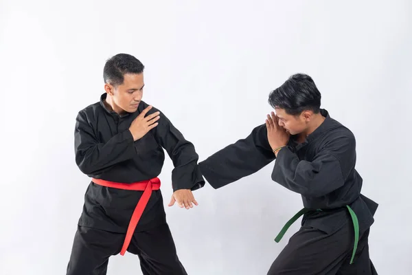 Dua pria Asia mengenakan seragam pencak silat berkelahi dengan meninju dan gerakan tangkisan bawah — Stok Foto