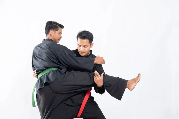 Dos luchadores en negro pencak silat lucha uniforme en cerraduras y portazos —  Fotos de Stock