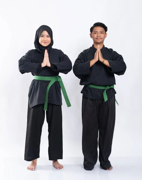 Des femmes et des hommes voilés en uniformes silat crayon avec ceintures vertes font des gestes de main respectueux — Photo