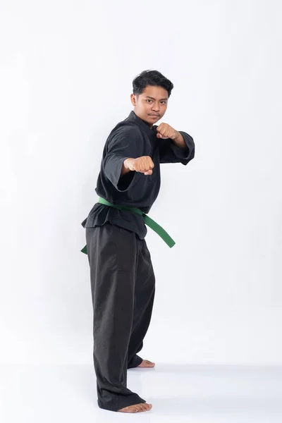 Jonge aziatische man in pencak silat uniform met side stance met beide handen gebald — Stockfoto