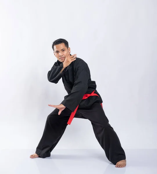 Asiatisk man med defensiv hållning när han bär en pencak silat uniform — Stockfoto