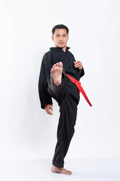 O homem no uniforme de silat pencak chuta para a frente com uma perna — Fotografia de Stock