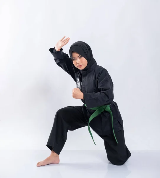 Azjatki w chustkach noszą pencak silat uniformy z przykucniętymi zielonymi pasami podczas wykonywania ruchów obronnych — Zdjęcie stockowe