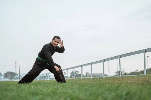 Un uomo che indossa un'uniforme di seta nera pencak con un movimento di posizione bassa — Foto Stock