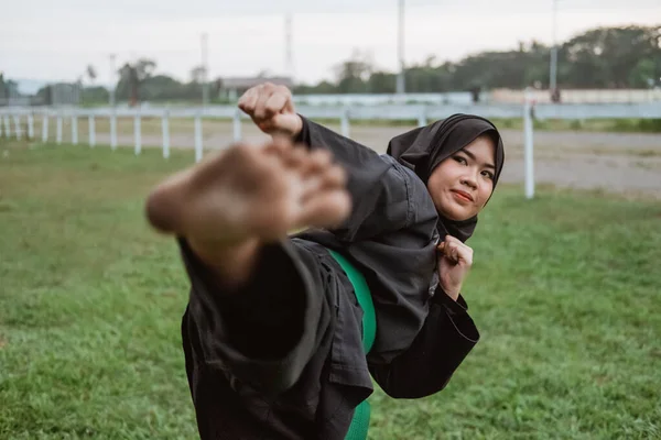 Primer plano de una mujer asiática con velo y un uniforme de pencak silat con movimiento de pasos — Foto de Stock