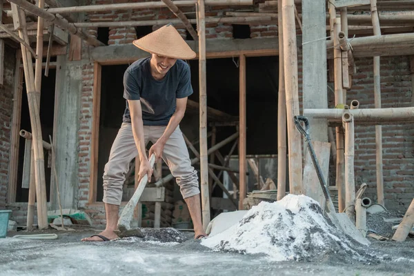 Albañil sosteniendo una azada para masa para arena y cemento para edificios — Foto de Stock