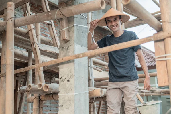 Construction workers smile at the camera as they stand between the bamboo and poles — Stock Photo, Image