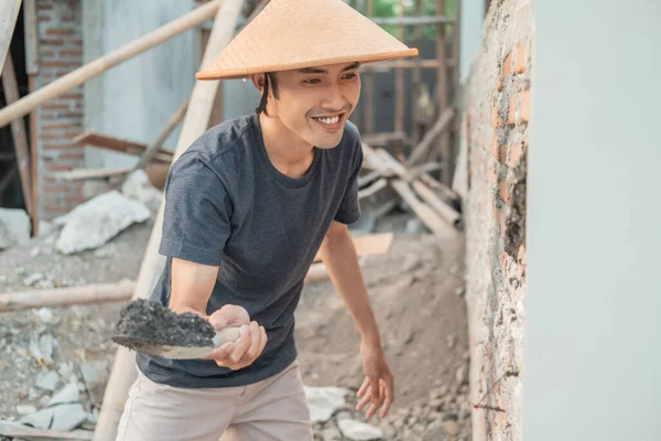 Trabajadores de la construcción asiáticos utilizan una tapa usando una cucharada para unir cemento a los ladrillos — Foto de Stock