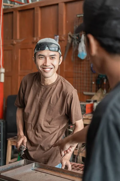 Soldador masculino sonríe cuando se le pide que trabaje de acuerdo con las órdenes del propietario del taller de negocios —  Fotos de Stock
