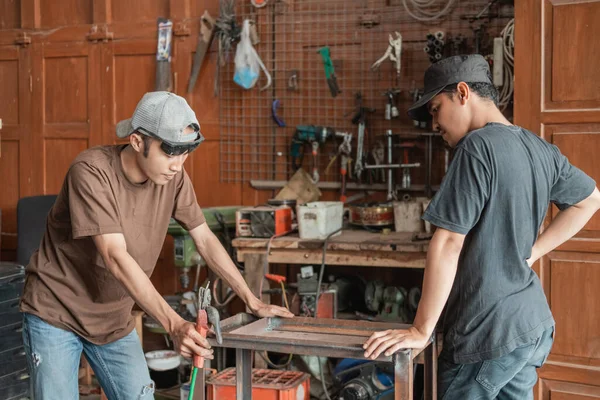 Cliente masculino ve a un soldador trabajando en un estante de metal —  Fotos de Stock