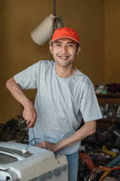 Trabalhadores eletrônicos sorriem para a câmera usando uma chave de fenda durante a reparação de uma máquina de lavar roupa — Fotografia de Stock