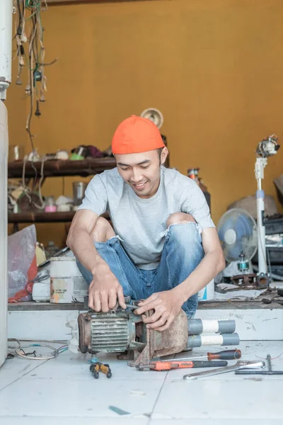 Asiático hombre electrónica trabajador celebración de agua bomba máquina para reparación —  Fotos de Stock