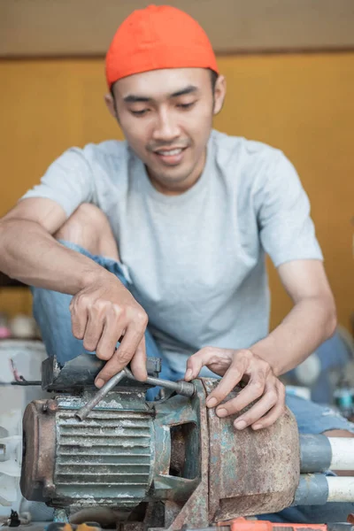 Asiatische männliche Elektroniker verwenden drei Kopfschlüssel, um Wasserpumpe Maschine zu reparieren — Stockfoto