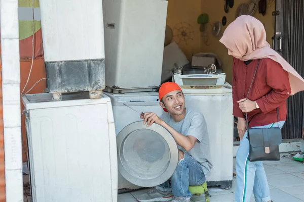 Perempuan jilbab mengambil mesin cuci rusak ke tukang reparasi elektronik — Stok Foto