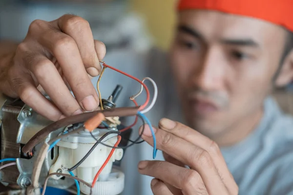 Kırık kabloları tamir eden Asyalı elektronik tamirciyi kapatın. — Stok fotoğraf