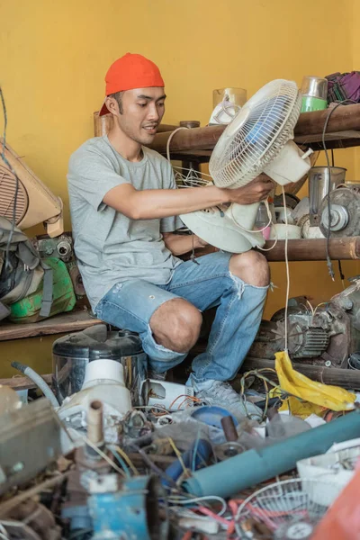 Asian electronics repairmen hold fans while sitting around electronic parts — Stock Photo, Image