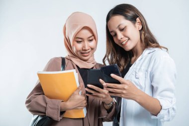 Çanta taşıyan ve cep telefonlarına bakan mutlu üniversite gençlerinin portresi