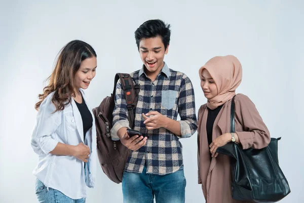 Retrato de jovens universitários felizes levando sacos e discussão olhando para telefones celulares — Fotografia de Stock